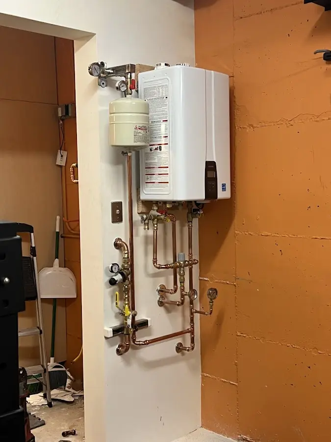 Plumbing technician inspecting water heater connections in Portage Lakes